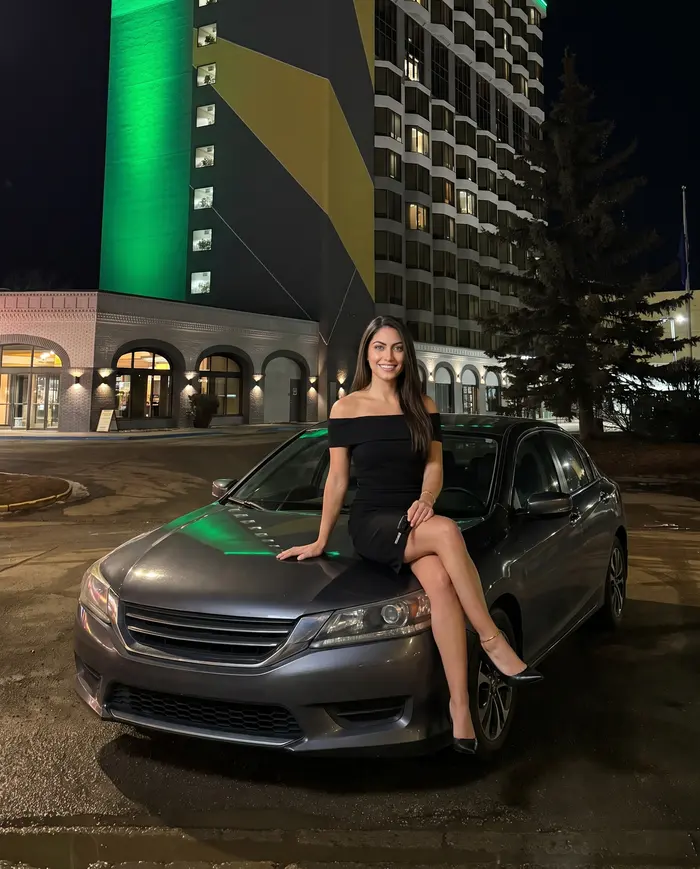 A woman on a car hood outside the hotel tower