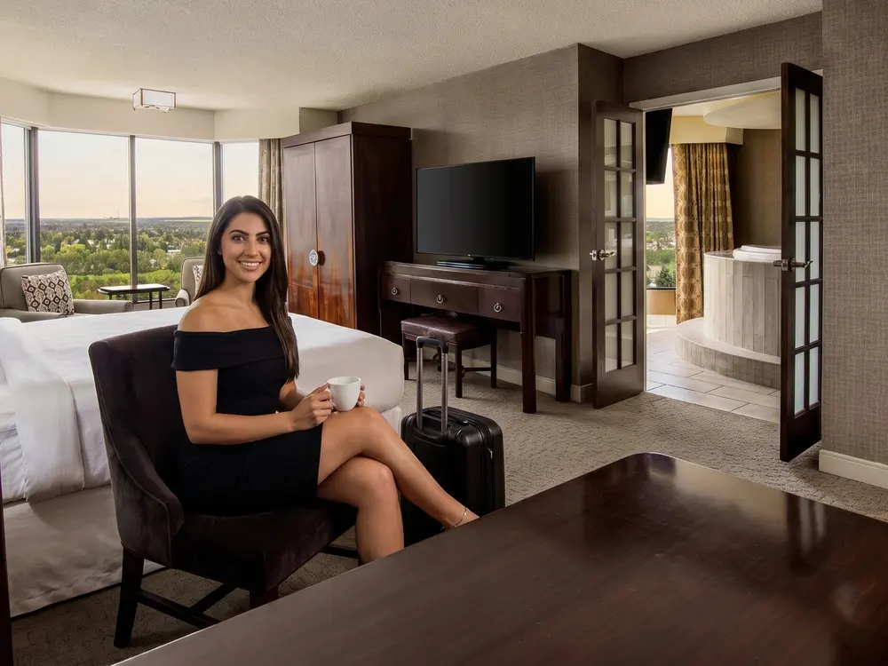 A woman with a cup and a suitcase in a hotel suite